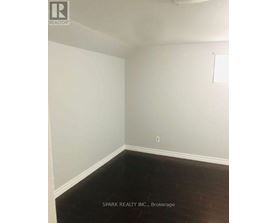 A white wall with a light switch and a dark floor.