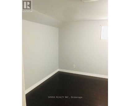 A white wall with a light switch and a dark floor.