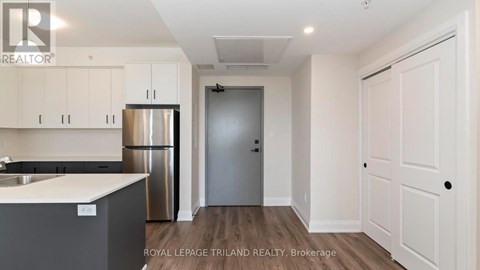 A kitchen with white cabinets and a stainless steel refrigerator.