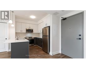 A modern kitchen with a refrigerator, microwave, and oven.