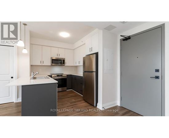 A modern kitchen with a refrigerator, microwave, and oven.