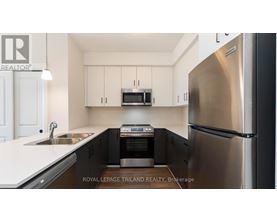 A modern kitchen with a stainless steel refrigerator and black cabinets.