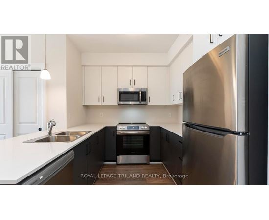 A modern kitchen with a stainless steel refrigerator and black cabinets.