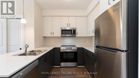 A modern kitchen with a stainless steel refrigerator and black cabinets.