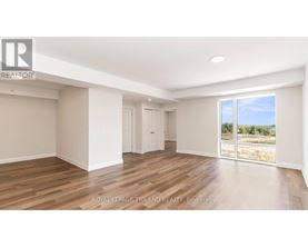 A spacious room with wooden flooring and white walls.