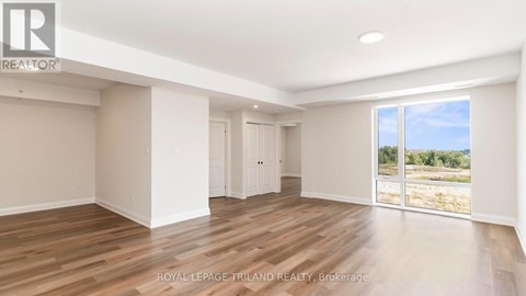 A spacious room with wooden flooring and white walls.