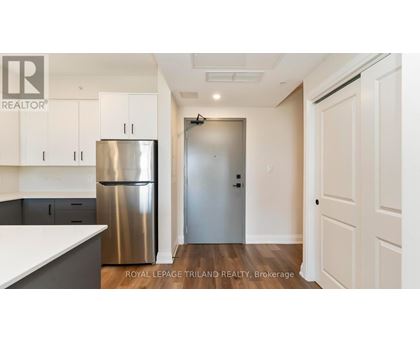 A kitchen with white cabinets and a stainless steel refrigerator.