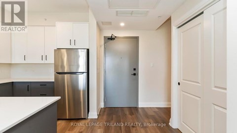 A kitchen with white cabinets and a stainless steel refrigerator.