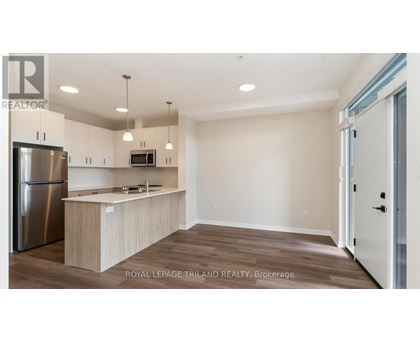 A kitchen with a refrigerator, microwave, and wooden cabinets.
