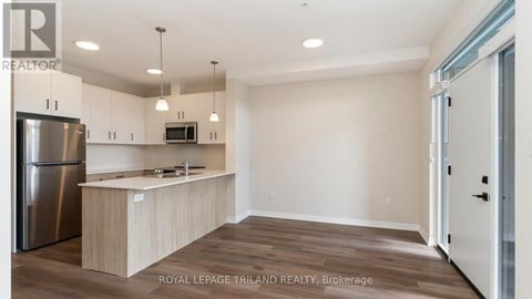 A kitchen with a refrigerator, microwave, and wooden cabinets.