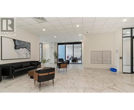 A spacious living room with a black sofa, a coffee table, and a large painting on the wall.