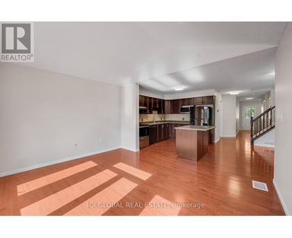 A spacious room with wooden floors and a staircase leading to another room.