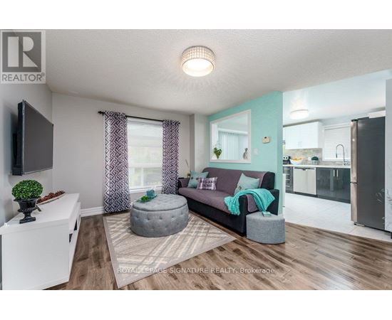 A living room with a grey ottoman and a grey couch with a green throw on it.