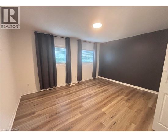A room with wooden flooring and a window with black curtains.