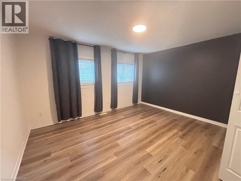 A room with wooden flooring and a window with black curtains.