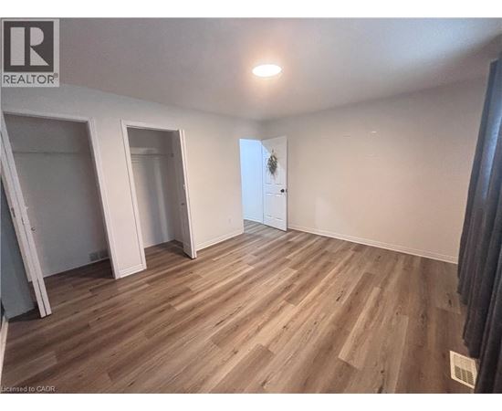 A room with wooden flooring and a door in the background.