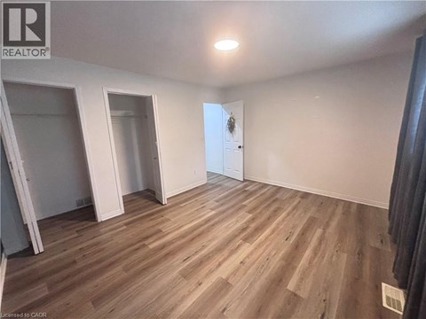 A room with wooden flooring and a door in the background.