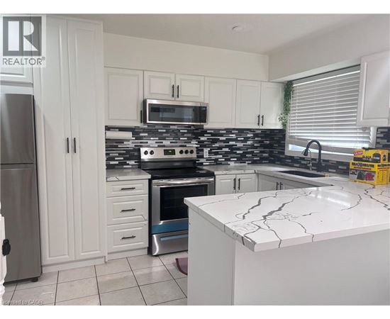 A kitchen with white cabinets and a black and white tiled backsplash.