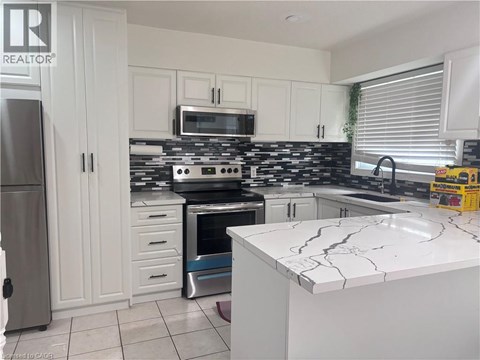 A kitchen with white cabinets and a black and white tiled backsplash.