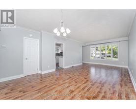 A spacious room with wooden flooring and a chandelier hanging from the ceiling.