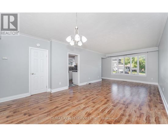 A spacious room with wooden flooring and a chandelier hanging from the ceiling.