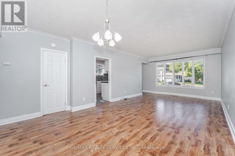 A spacious room with wooden flooring and a chandelier hanging from the ceiling.
