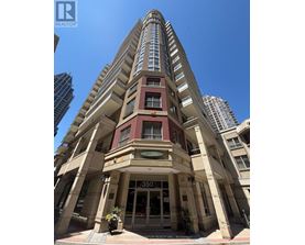 A tall building with a red and beige facade stands in front of other buildings.
