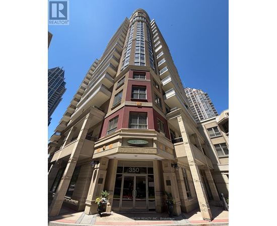 A tall building with a red and beige facade stands in front of other buildings.