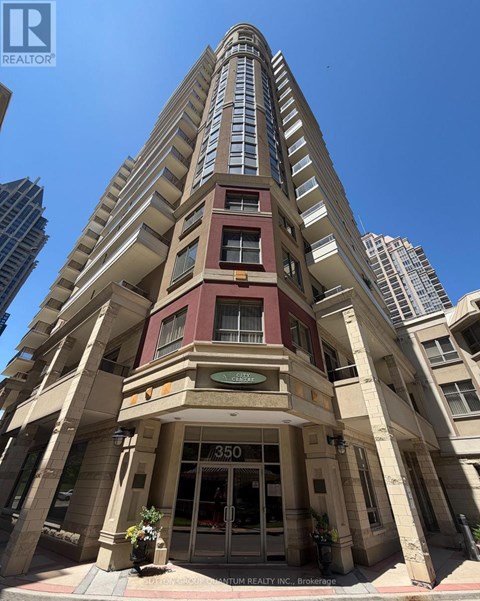 A tall building with a red and beige facade stands in front of other buildings.