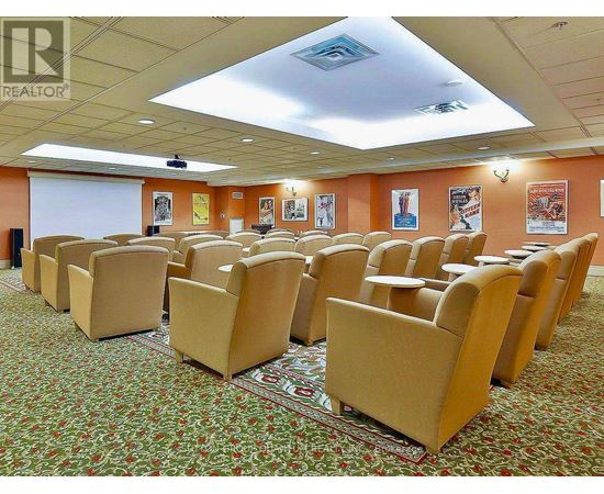 A conference room with rows of chairs and a projector screen.