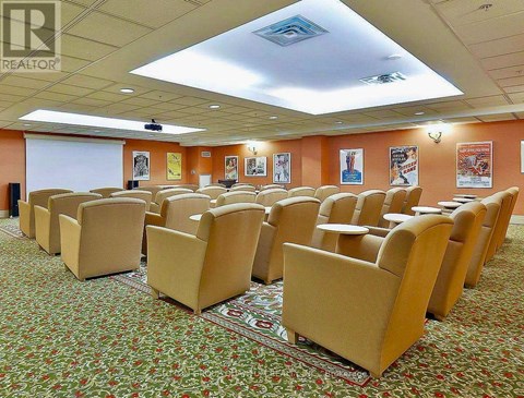 A conference room with rows of chairs and a projector screen.