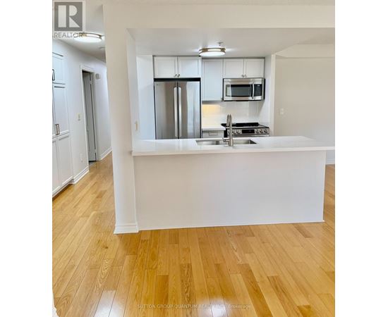 A kitchen with a white counter top and stainless steel appliances.