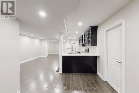 A spacious kitchen with white walls and a black countertop.
