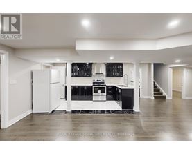 A spacious kitchen with white cabinets and black appliances.