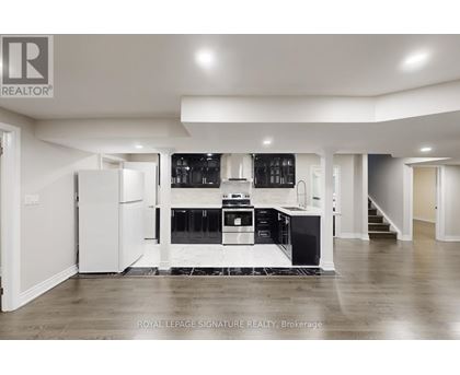 A spacious kitchen with white cabinets and black appliances.