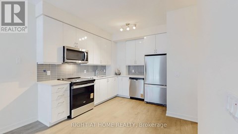 A modern kitchen with white cabinets and stainless steel appliances.