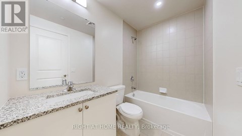 A white bathroom with a marble countertop and a bathtub.