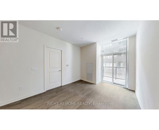 A room with a door and a window with a view of a building outside.