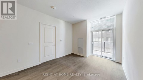 A room with a door and a window with a view of a building outside.