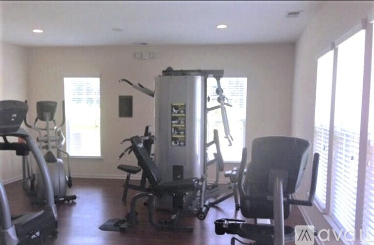 A gym with a treadmill, elliptical machines, and a weight machine.