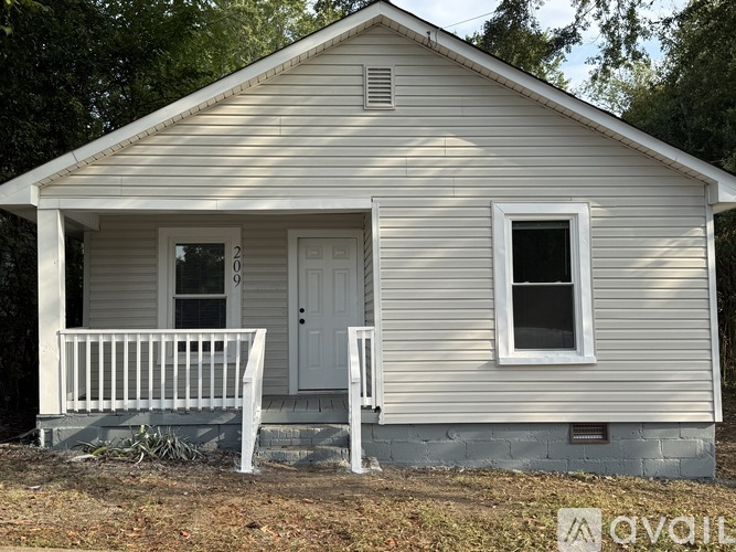 A small white house with a porch and a door.