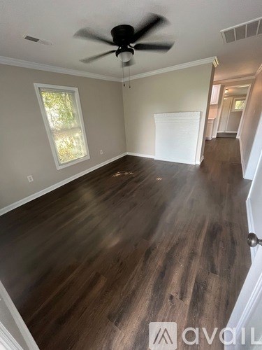 A room with a ceiling fan and wooden flooring.