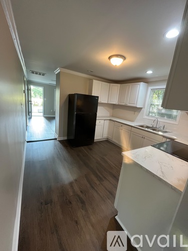 A kitchen with a black fridge and wooden floors.