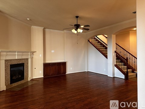 A spacious living room with a fireplace and a staircase.