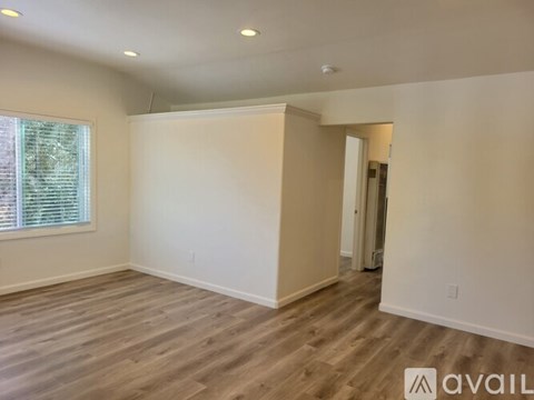A spacious room with wooden flooring and white walls.