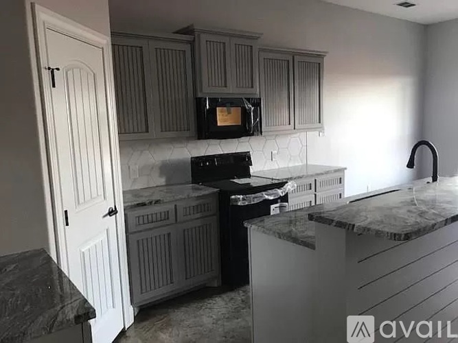 A kitchen with a black stove top oven and white cabinets.