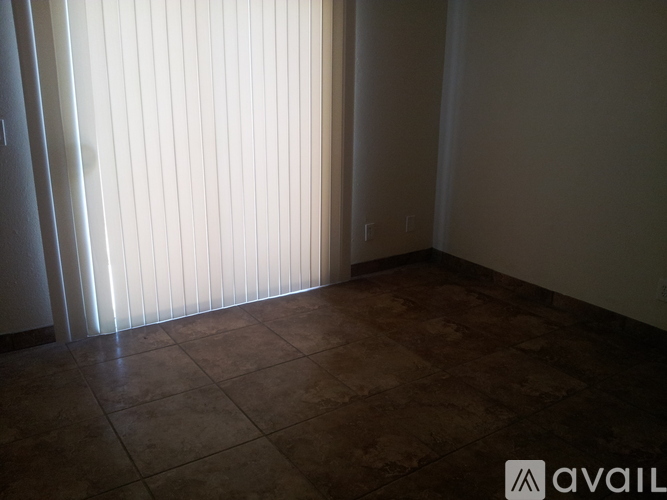 A room with a tiled floor and a window with blinds.
