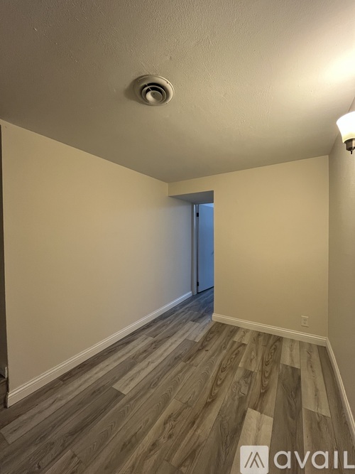 A room with a light brown wooden floor and a white ceiling with a light fixture.
