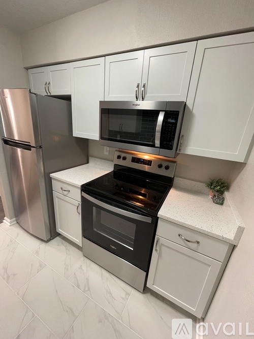 A kitchen with white cabinets and a stainless steel refrigerator.