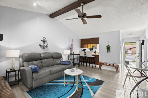 A living room with a grey sofa and a blue rug.